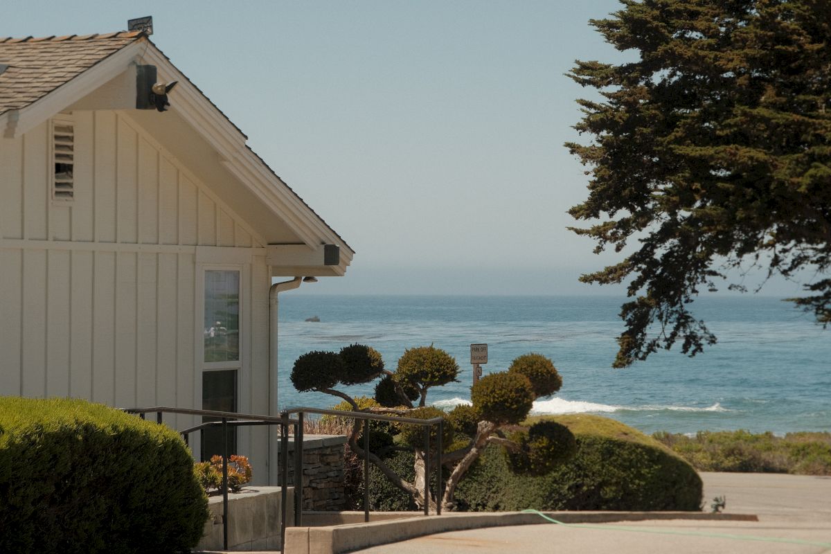 A white building with a brown roof and a view of the ocean