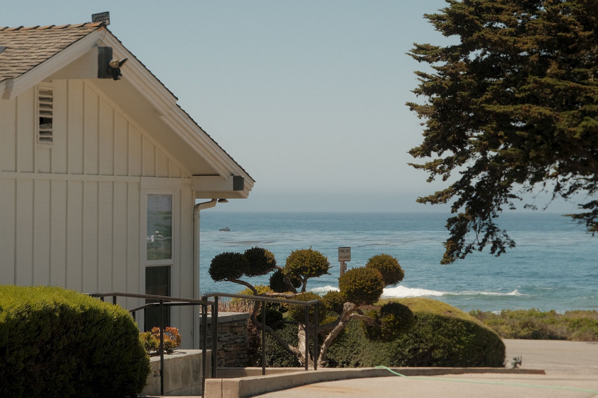 A white building with a gable roof and a view of the ocean.