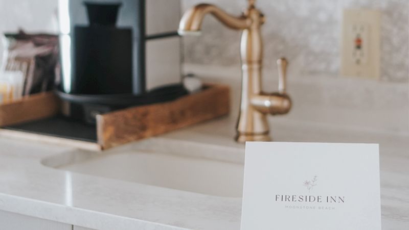 A hotel amenity card on a countertop with a coffee maker and sink in the background.